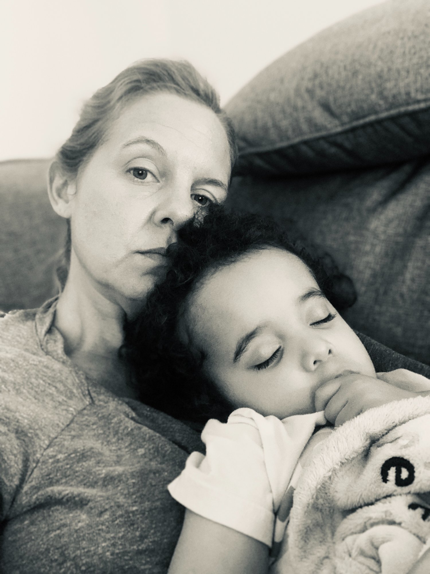 A quiet moment — parent holding a sleeping child on the couch